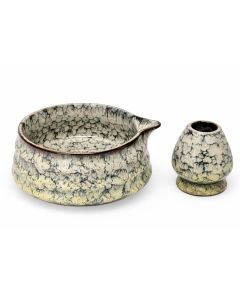 Matcha kom met schenktuit en bijpassende houder van keramiek met geel gemêleerd glazuur, vrijstaand gefotografeerd.