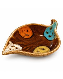 Keramieken bladschaaltje in natuurkleuren met glanzend bruin glazuur en decoratieve accenten in oranje, turquoise, crème en geel op een witte achtergrond.