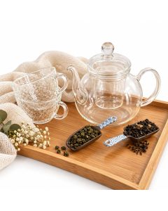 Theepakket Oolong Way met transparante glazen theepot en uitneembaar theefilter, twee glazen theekopjes met reliëf en twee schepjes losse thee op een bamboe dienblad.